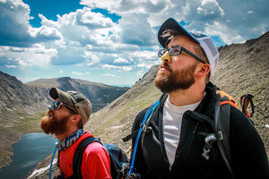 Two men on an outdoor trek wearing Nöz yellow and blue reef safe sunscreen on their noses