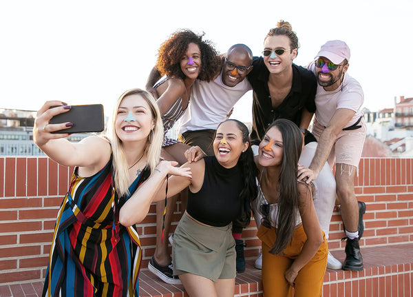 A group of young people pose for a picture wearing environmentally friendly Nöz sunscreen in a variety of colors.